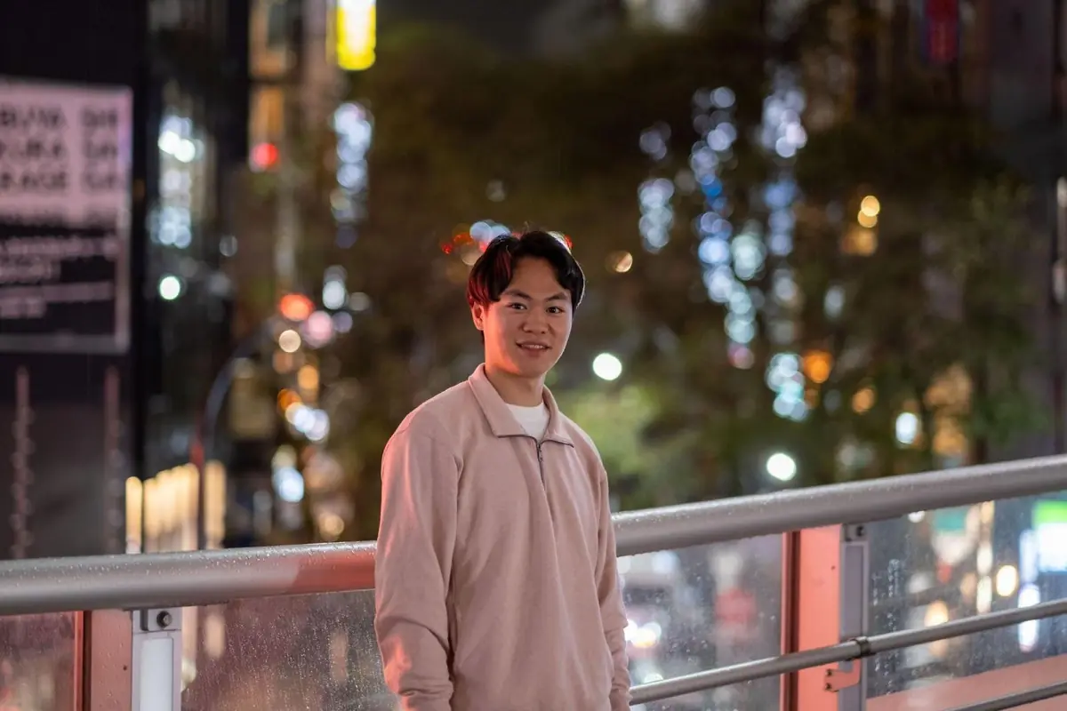 渋谷の夜の歩道橋に立つ長谷川雄飛